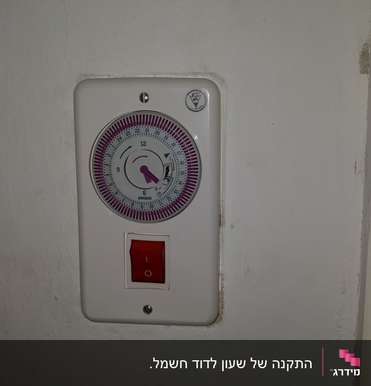 טיימר חשמלי עם מתג אדום על קיר לבן